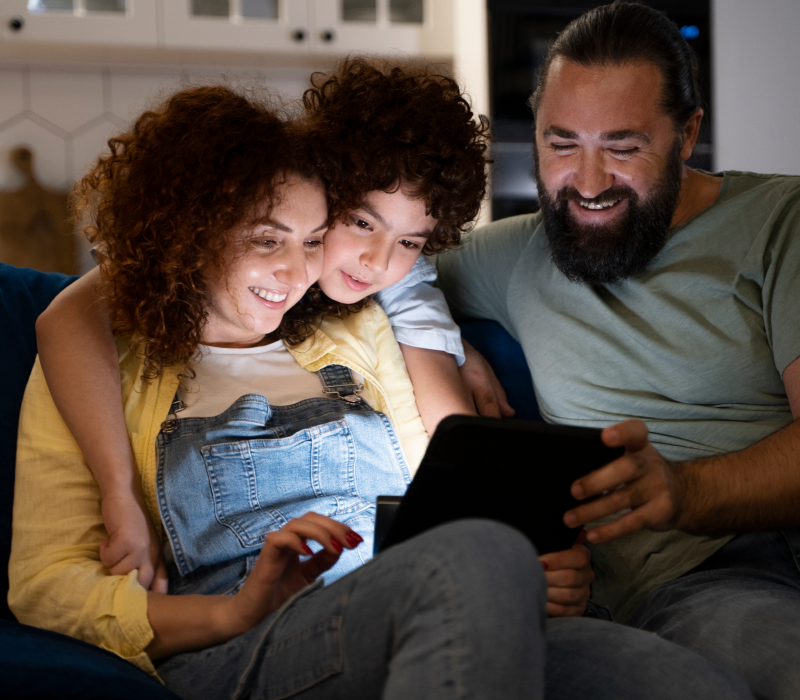 Família reunida assistindo conteúdo no tablet usando o UniTV App para teste grátis IPTV.